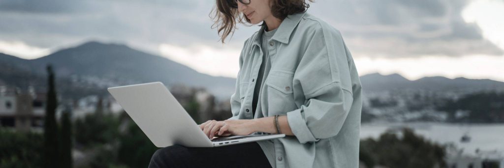 Frau arbeitet mit Laptop vor Berglandschaft