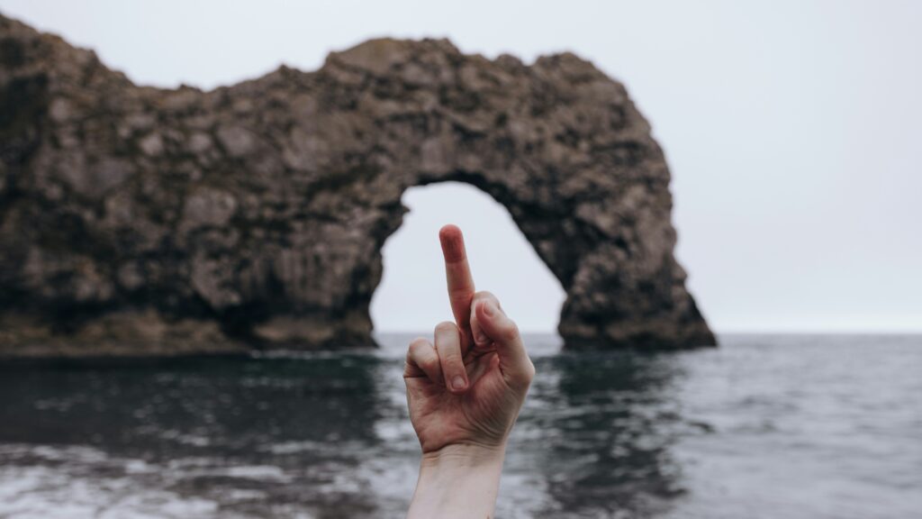 Ein Mittelfinger wird als Zeichen von Ragebait im Meer in die Höhe gehalten.